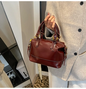 Detail der weinroten Boston-Tasche aus Ölwachsleder mit Goldring und Tragegriffen
