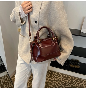 Detail of burgundy leather tote bag with white contrast stitching and shoulder strap