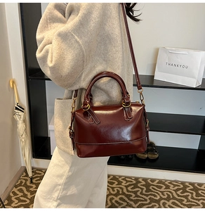 Detail view of burgundy leather Boston bag showing sleek finish and white stitching details
