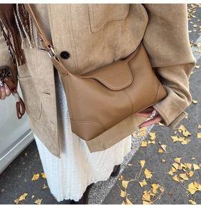 Close-up of retro brown crossbody bag with litchi texture and metal buckle on street