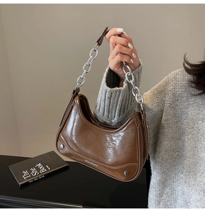 Detailed view of brown patent leather hobo bag with a silver metallic chain strap