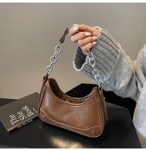 Close-up of brown cracked leather hobo bag with vintage metal chain and handle detail