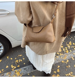 Close-up of brown litchi grain leather crescent bag styled with a beige trench coat