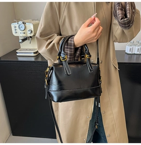 Detailaufnahme einer schwarzen Lackleder-Handtasche mit weißen Kontrastnähten und Goldringen
