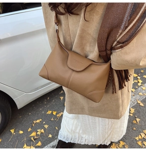 Brown leather underarm bag detail showing textured finish and fashion logo engraving