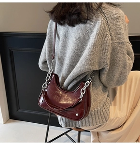 Detail of burgundy patent leather shoulder bag with silver chain on model back view