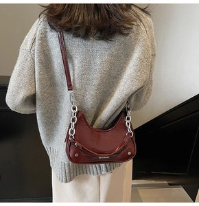 Detail of burgundy crescent shoulder bag with silver chain and glossy patent leather