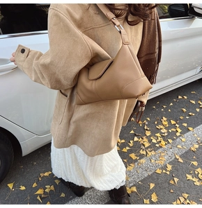 Close-up of khaki pebbled leather shoulder bag with wide strap and flap closure details