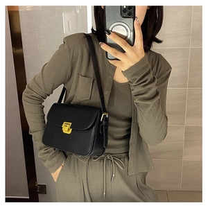 Mirror selfie showing the black leather crossbody bag with gold buckle on a model