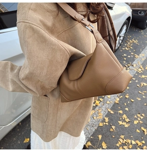 Detailed macro of brown lychee leather shoulder bag with embossed texture and wide strap