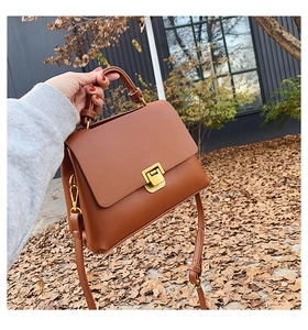 Détail du sac en cuir caramel avec fermoir rotatif doré et poignée supérieure robuste