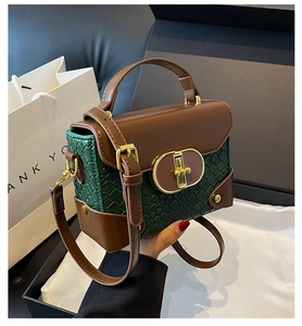 Detail of vintage green woven handbag showing golden twist lock and brown leather handle
