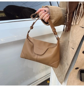 Detail of caramel brown lychee leather handbag with adjustable strap and embossed text