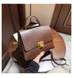 Gros plan d'un sac vintage marron avec fermoir doré posé sur une table en bois