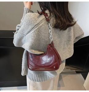 Close-up of wine red oil-wax leather shoulder bag with silver chain strap and rivet details