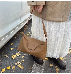 Close-up of caramel brown lychee grain leather shoulder bag with debossed fashion logo