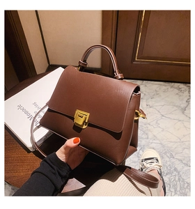 Close-up of brown leather bag featuring a gold rectangular twist lock and top handle