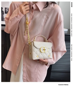 Detail of cream quilted mini handbag with gold chain and metal twist lock closure