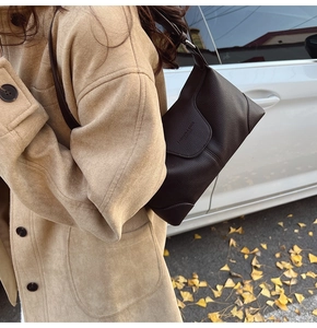 Close-up of litchi texture on dark brown leather shoulder bag with embossed fashion text