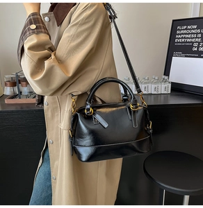 Detail of black leather Boston bag with contrast white stitching and gold hardware