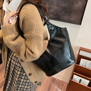 Grote zwarte hobo tas van PU-leer met patchwork ontwerp vanaf de zijkant gefotografeerd