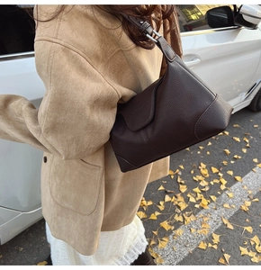 Detail of dark brown lychee leather shoulder bag on model in autumn street setting