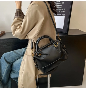Detail of black oil wax leather Boston bag with white stitching and gold hardware