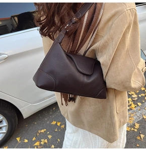 Outdoor lifestyle shot of a dark brown litchi pattern leather shoulder bag with flap