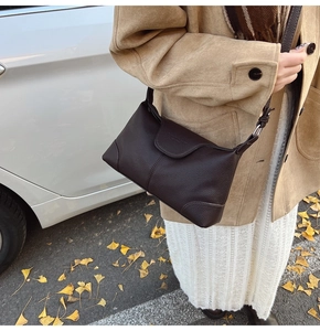 Close-up of dark brown lychee grain leather shoulder bag with natural texture and stitching