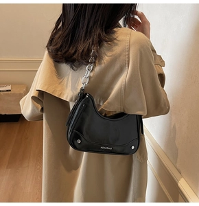 Détail d'un sac hobo noir avec bandoulière en chaîne argentée et accents de rivets en métal