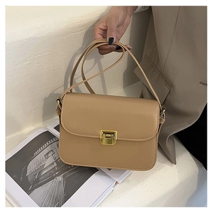 Detail view of a beige minimalist crossbody bag with gold metallic rectangular lock