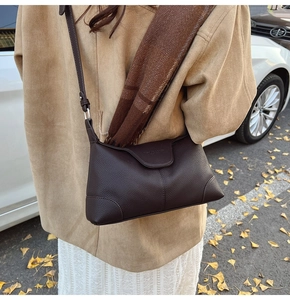 Detail of dark brown lychee leather crossbody bag on autumn street background