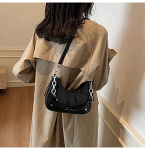 Detail of black patent leather hobo bag with bold silver chain and crossbody strap