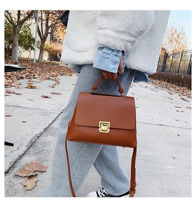 Détail du sac bandoulière en similicuir caramel avec fermoir doré et poignée supérieure
