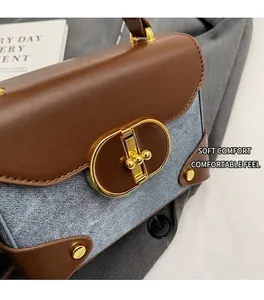 Close-up of retro color-block handbag with light blue denim fabric and brown leather details