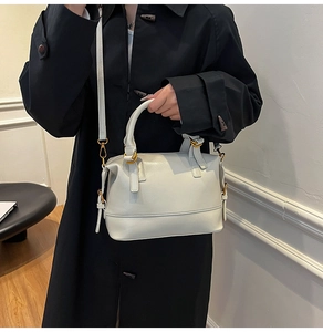 Detail of cream Boston bag featuring golden metal buckles and detachable shoulder strap