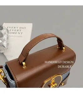 Close-up of the vintage handbag top handle featuring dark brown leather and blue denim stitching