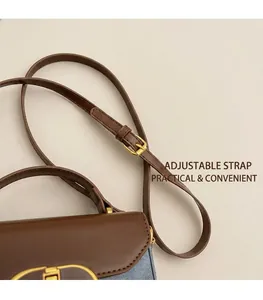 Detail view of the adjustable shoulder strap and gold hardware on blue denim bag
