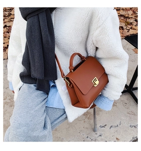 Détail du sac à main en cuir marron caramel avec boucle dorée et poignée supérieure