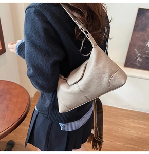 Close-up of beige lychee grain leather shoulder bag with adjustable strap and curved design
