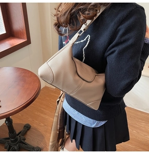 Detail of lychee pattern leather shoulder bag in beige with stitching and adjustable strap