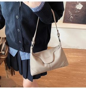 Detail of lychee pattern leather handbag with adjustable strap on a female model