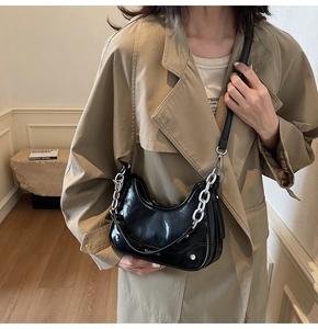 Détail du sac demi-lune en cuir verni noir avec chaîne argentée et clous métalliques