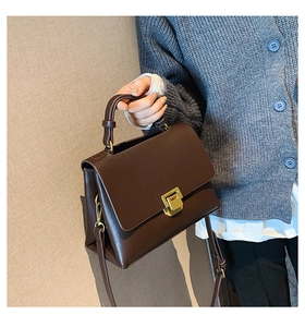 Detail der vintage dunkelbraunen Trapez-Tasche aus Kunstleder mit goldenem Metallverschluss