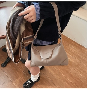 Close-up of pebble leather texture and embossed logo on minimalist beige shoulder bag