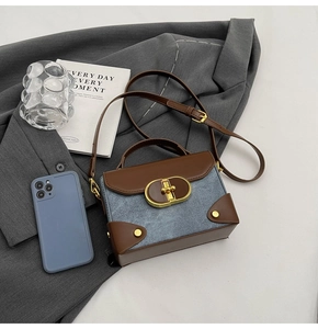 Close-up of blue denim and brown leather handbag with gold metal twist lock