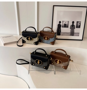 Detail view of four textured leather crossbody bags with golden oval buckles on steps