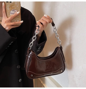 Detail of dark brown glossy hobo bag featuring silver metal chain and brand logo