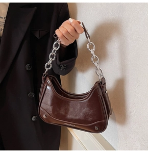Detail of silver chain strap and brand logo on dark brown glossy half-moon bag