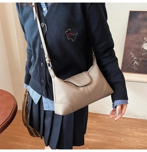 Detail of taupe litchi grain leather shoulder bag featuring fine stitching and flap closure